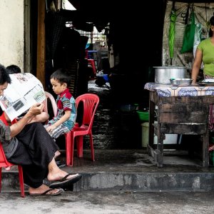Man reading newspaper at a food stall in Yangon