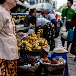Older woman walking in front of fruits