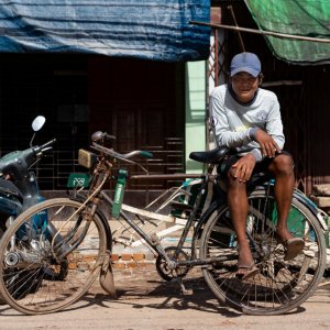 Young man waiting for customers with sitting on well-worn pedicab