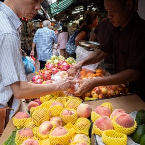 Man buying peach in a fruit shop