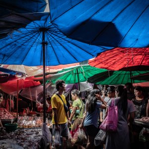 Shoppers wriggling under colorful parasols in Khlong Toei Market