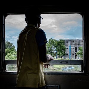 Man gazing out the car window on Maeklong Railway