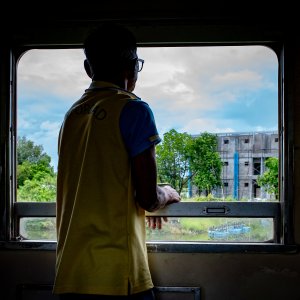 Man gazing out the car window on Maeklong Railway