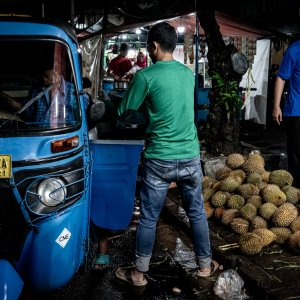 Men loading durians onto Bajaj