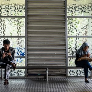 Man and woman sitting on the bench at the bus stop