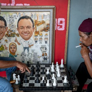 Men playing chess beside a paiting