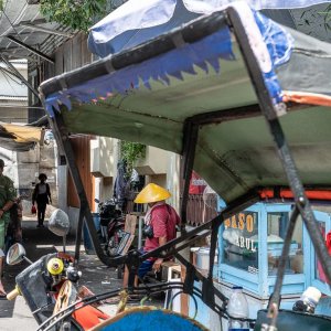 Becak, food stall, and people on the side of the road