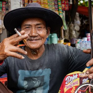 Becak driver in a hat smoking a cigarette