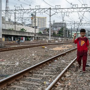 Boy walking beside the railroad tracks, thinking