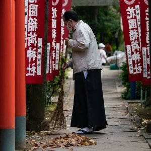 花園稲荷神社の参道を箒で掃く禰宜