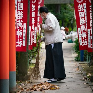 Priest sweeping the approach to Hanazono Inari Shrine with a broom