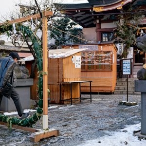 Man passing through the thatch ring at Hirakawa Tenmangu Shrine