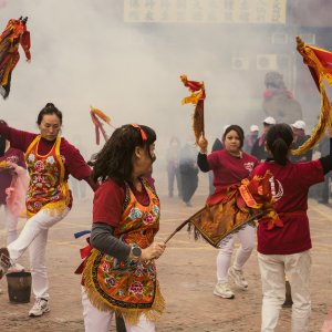 煙の中で旗の付いた棒を手にして踊る女性たち