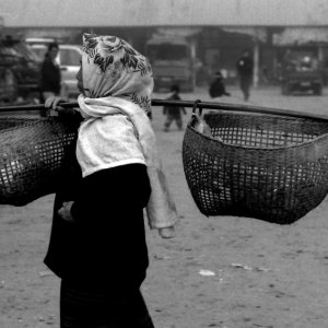 市場の中を天秤棒を担いで歩いていた女性