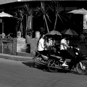 日傘を差しながらバイクに乗る女性