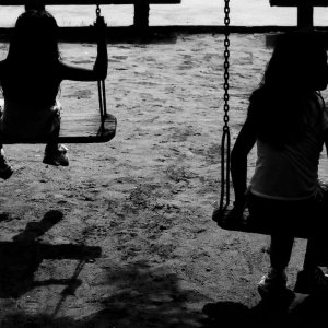 Silhouetted girls playing on swing