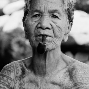 Tattooed older woman puffing on pipe