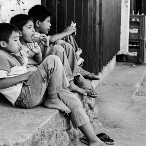Three boys sitting by the wayside