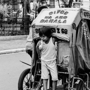 Boy getting on back of tricycle