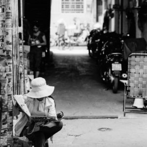 Hatted woman reading newspaper