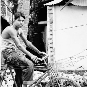 Young man astride a tricycle with a cargo bed