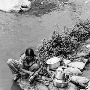 Woman washing dishes with river water