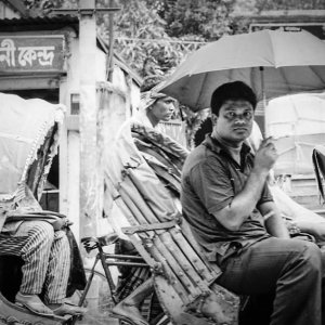 Passenger on cycyle rickshaw putting umbrella up