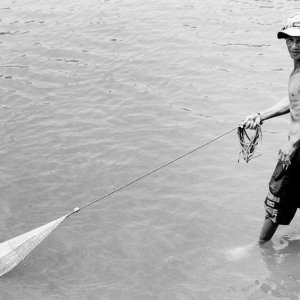 川に入って漁網を引っ張る男