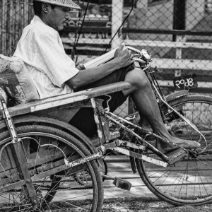 Pedicab driver reading.