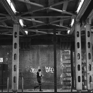 Man walking dim railway underpass