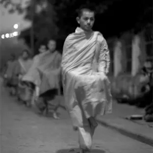 Buddhist monks walking dim street for alms
