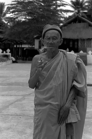 境内で煙草を吹かす年配の僧侶