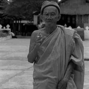 Old monk smoking cigarette in precinct