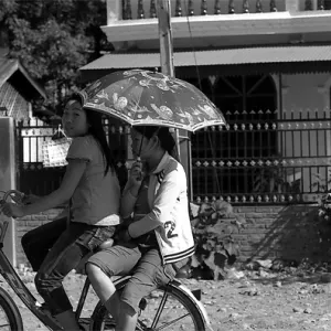 日傘を差しながら自転車に二人乗りする女の子