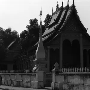 寺院の横を日傘を差して歩く僧侶