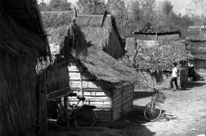 Young man walking between thatched huts