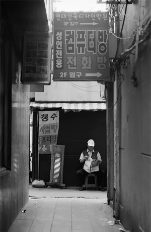 路地裏で新聞を読む男