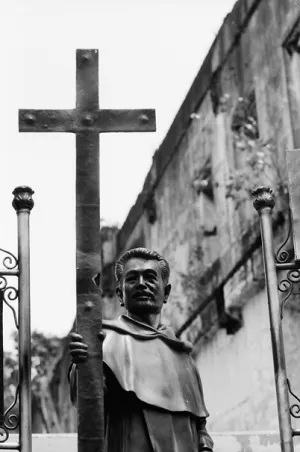 手に大きな十字架を持つ聖職者の像
