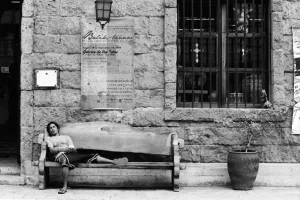 お土産屋の前に置かれたベンチで昼寝していた男