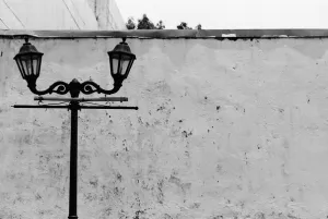 Street lamp standing in front of tall wall