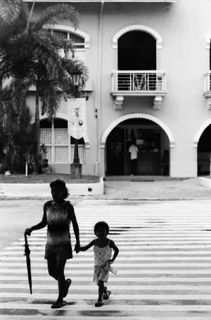 Parent and child crossing street with closed umbrella
