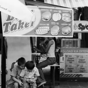 Boys playing hand-held game in front of food stall