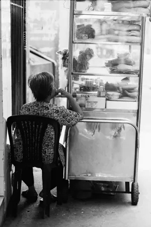 Older woman sitting beside glass box