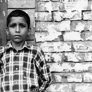 Boy standing against brick wall