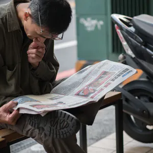 Man with old eyes reading a newspaper