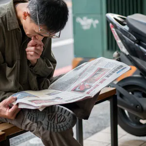 Man with old eyes reading a newspaper