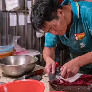 Fishmonger filleting fish into three pieces