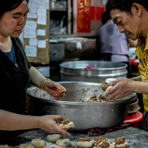 Man and woman making meat buns one after another