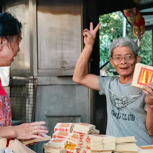 Man making a peace sign with joss papers in his hand