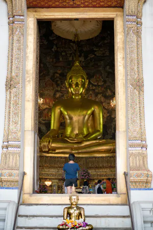 two Buddha statues and a worshiper